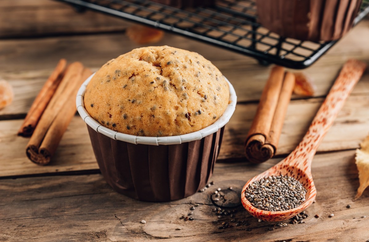 Ein Zimtmuffin. Daneben liegen ein Löffel Chiasamen und einige Zimtstangen.