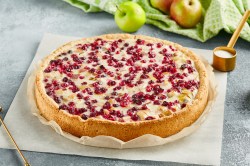 Ein ganzer Apfel-Cranberry-Kuchen auf einem Stück Backpapier.