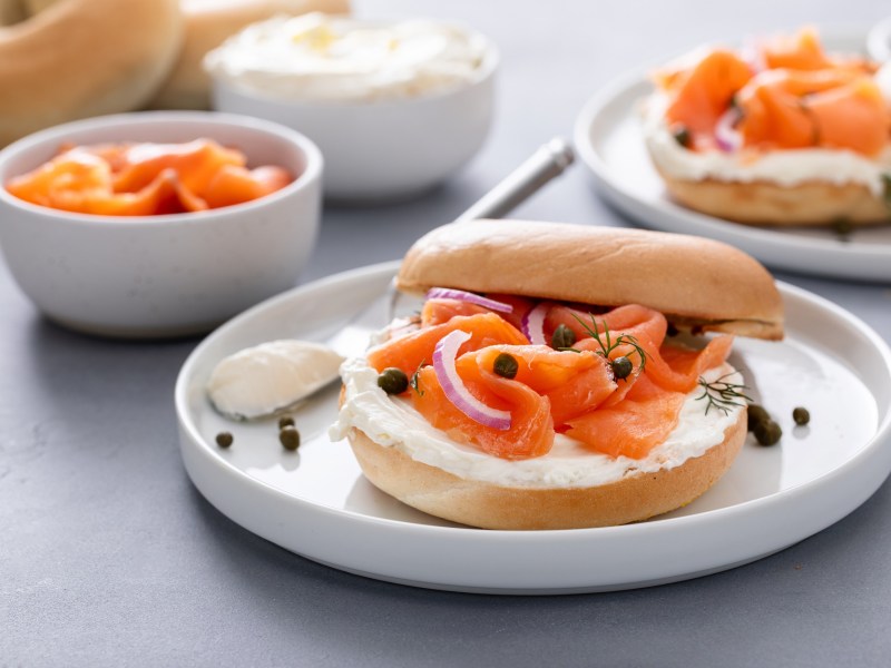 Räucherlachs-Bagels mit Kapern und Dill auf mehreren Tellern.