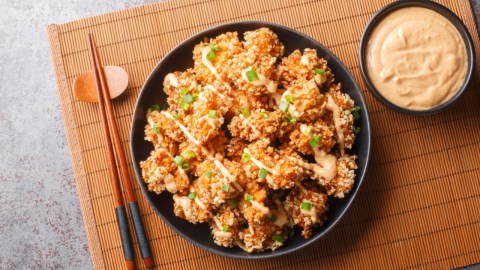 Bang Bang Chicken auf einem Teller in der Draufsicht. Daneben ein Schälchen mit Soße.