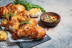 Harissa-Hähnchen vom Blech, serviert mit Zitronenspalten und Kirschtomaten.