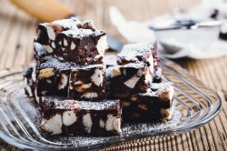 Einige Stücke Rocky-Road-Schokoriegel mit Marshmallows auf einem Glasteller.