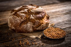Buchweizen-Quark-Brot mit umherliegenden Buchweizenkörnern auf einem Holztisch.