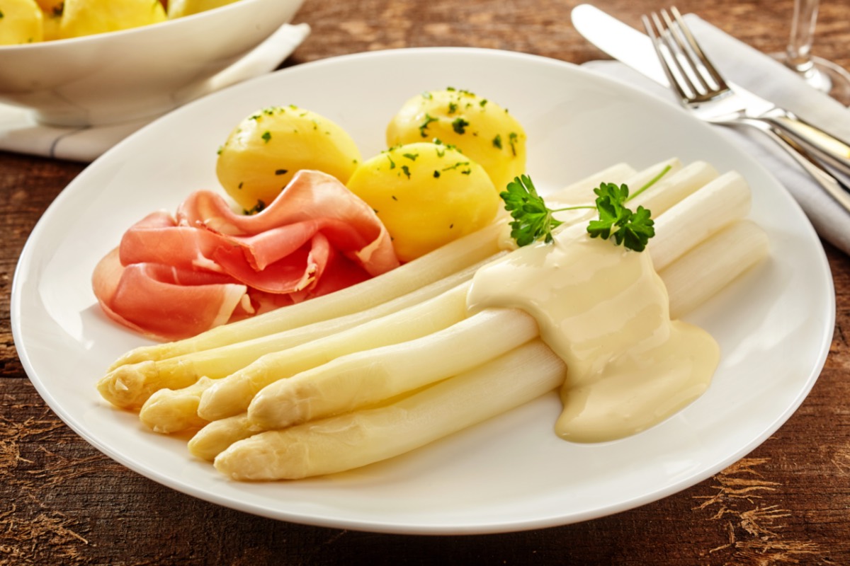 Wie viel Spargel pro Person: eine Portion Spargel mit Sauce hollandaise und Kartoffeln auf einem Teller.