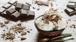 3 Kugeln Eierlikör-Eis mit Schokolade in einer Schüssel, drumherum Schokolade.