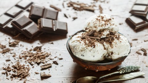 3 Kugeln Eierlikör-Eis mit Schokolade in einer Schüssel, drumherum Schokolade.